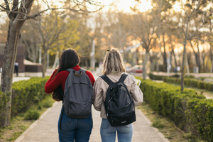students walking on campus wearing backpacks